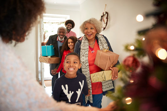 A family enters a home with gifts during the holidays