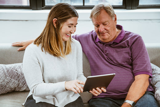 Woman and man sitting on couch looking at a tablet