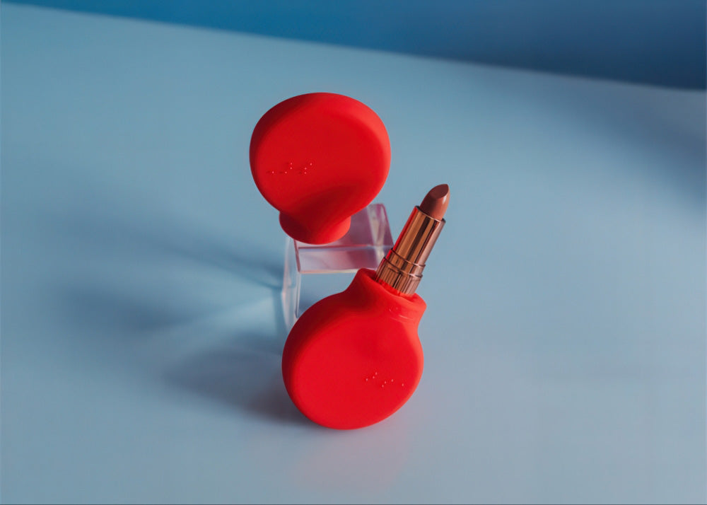 Two red makeup grippers, one with a lipstick tube inserted, on a blue background