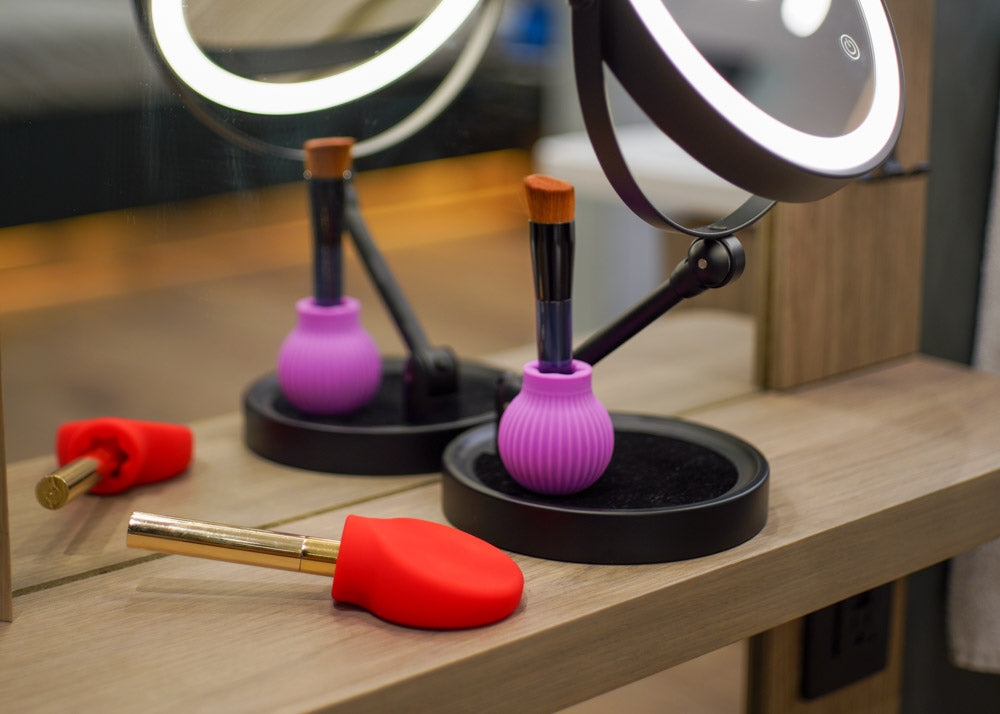 Makeup grips in front of a vanity mirror with ring light.