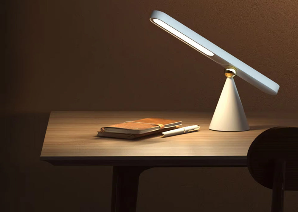 Modern desk lamp on a wooden surface with a dark background