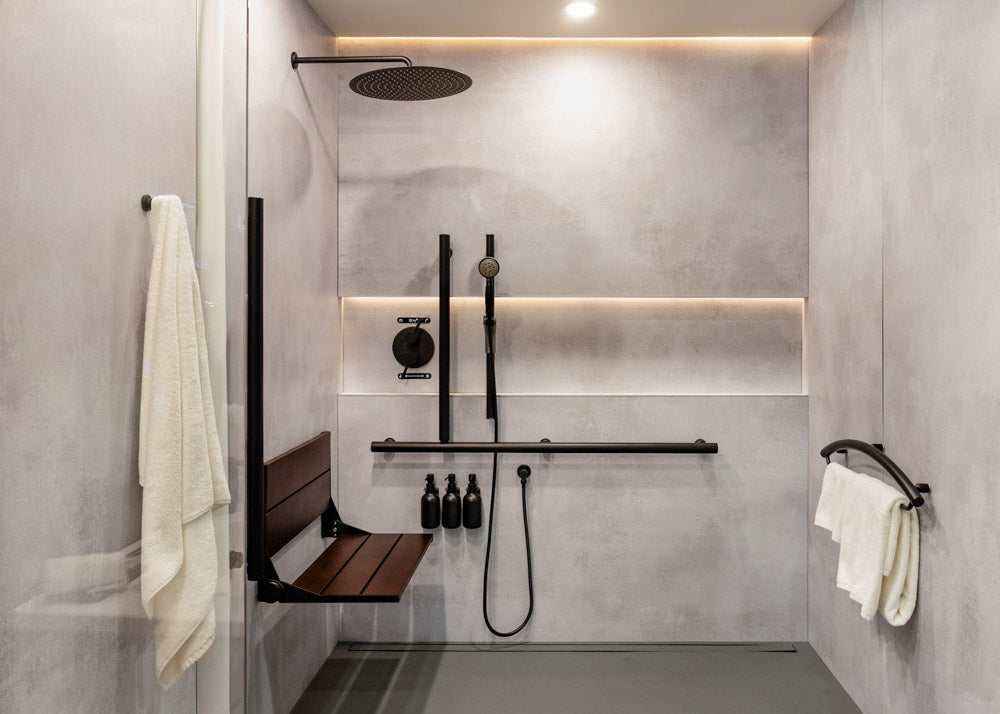 Modern shower setup with bench, handrails, and toiletries in a tiled bathroom.
