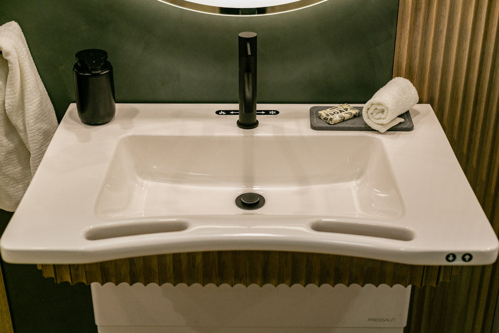 White sink with black faucet and accessories on a bathroom counter.