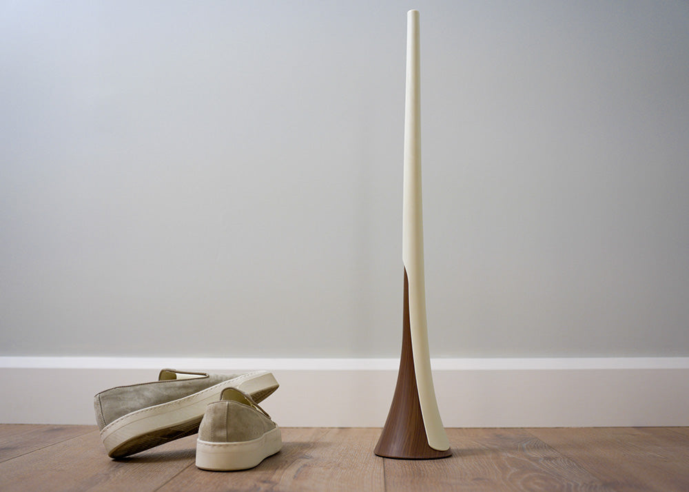 loafers next to a long white shoehorn resting on a wooden looking base