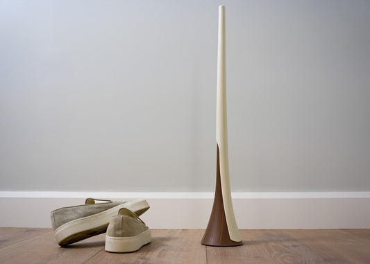 loafers next to a long white shoehorn resting on a wooden looking base