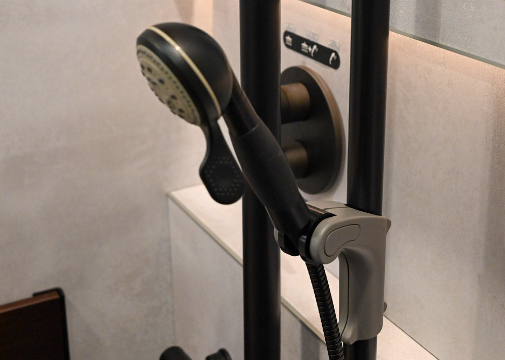 Handheld shower with hose attached to a sliding holder on a grab bar in a bathroom setting.