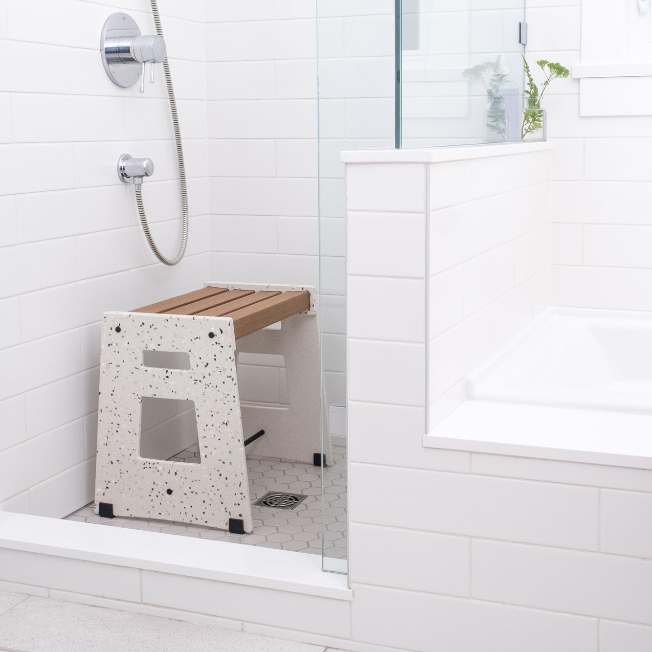 Lotic Shower Seat in terrazzo sitting in a white tiled shower.