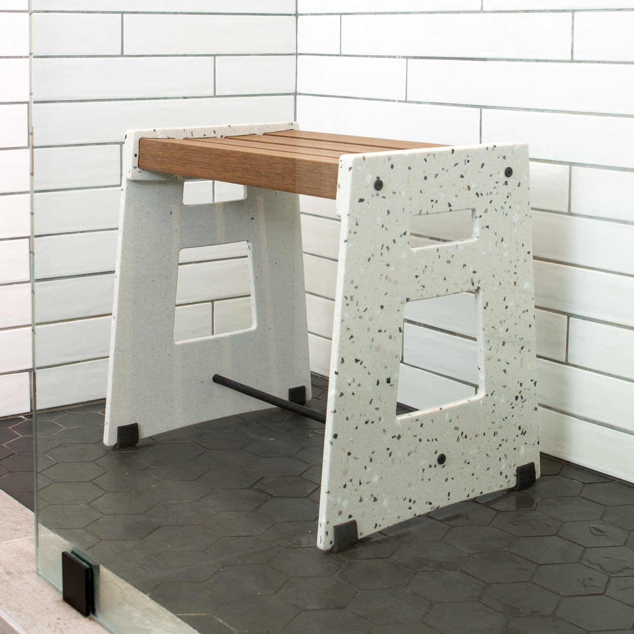 Lotic Shower Seat in Terrazzo in a shower with white tiled walls and a black tiled floor.