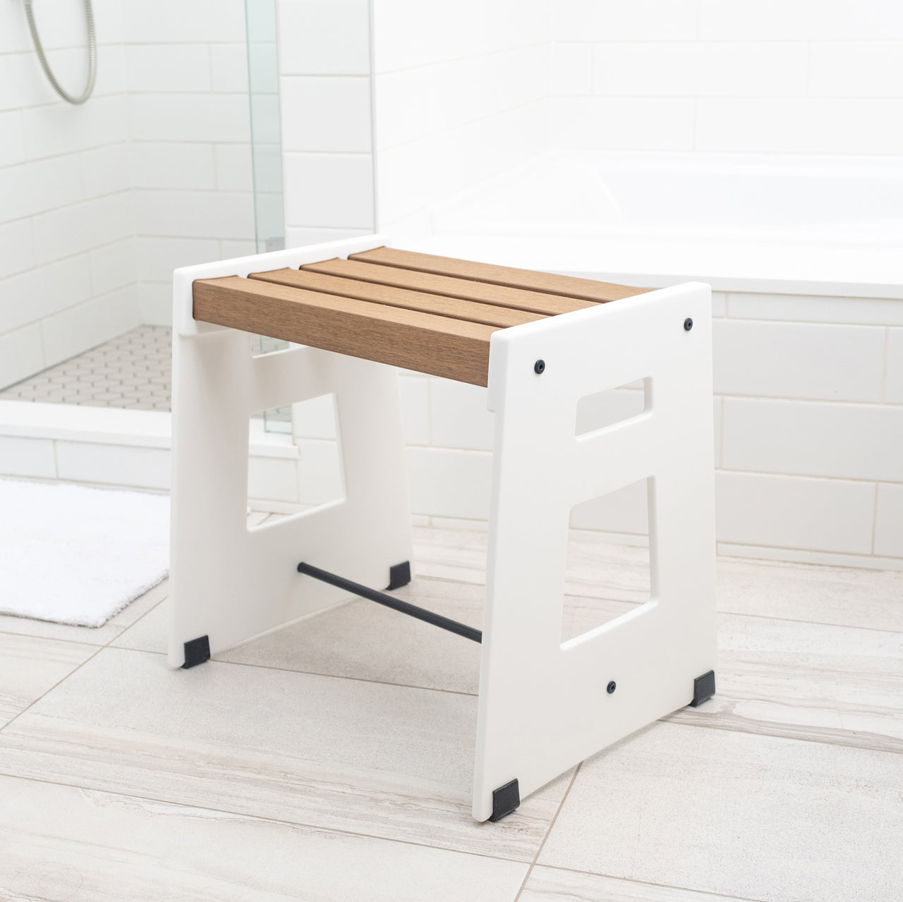 The Lotic Shower Seat in white sitting on the floor of a bathroom.