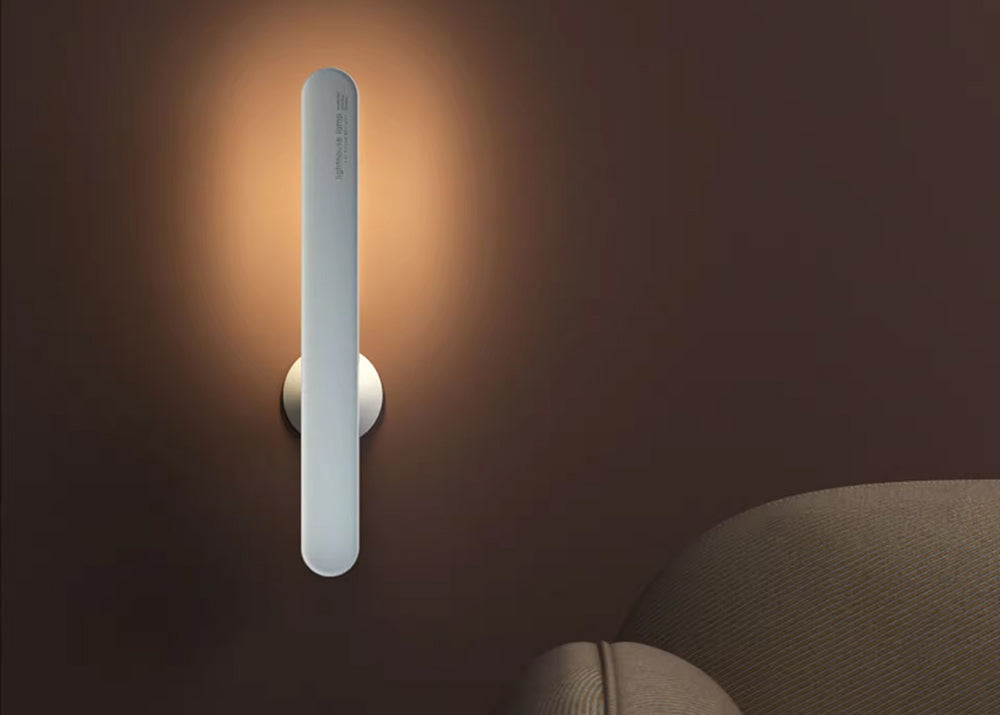 Modern wall light fixture on a dark wall with a soft glow.